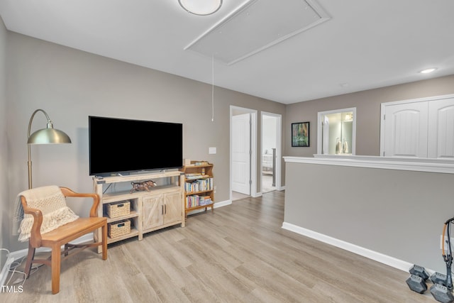 living room with attic access, baseboards, and light wood-type flooring