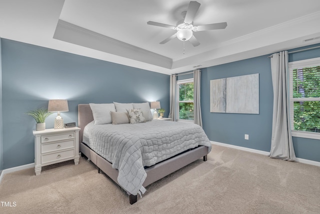 bedroom with a tray ceiling, crown molding, carpet, baseboards, and ceiling fan
