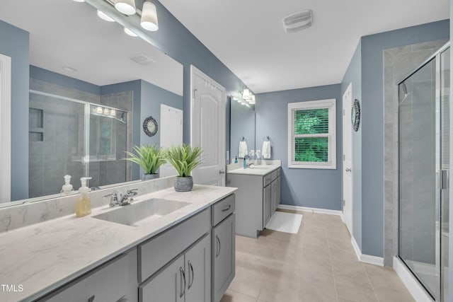 full bathroom featuring a shower stall, tile patterned flooring, two vanities, and baseboards