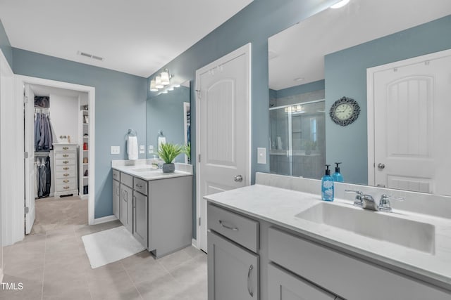 full bathroom with a shower stall, two vanities, tile patterned flooring, a walk in closet, and washer / dryer