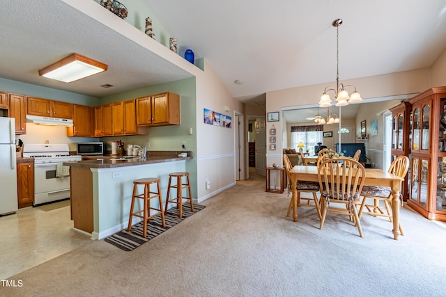 dining area featuring a chandelier, light carpet, baseboards, and vaulted ceiling