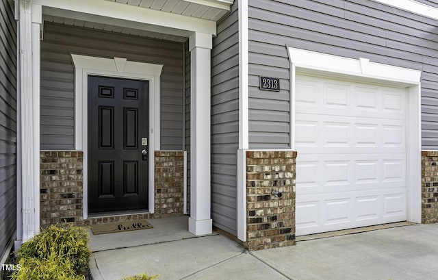 view of exterior entry featuring a garage and brick siding