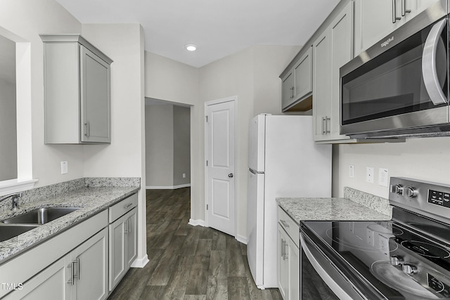 kitchen featuring stainless steel appliances, dark wood-style floors, light stone counters, gray cabinets, and recessed lighting