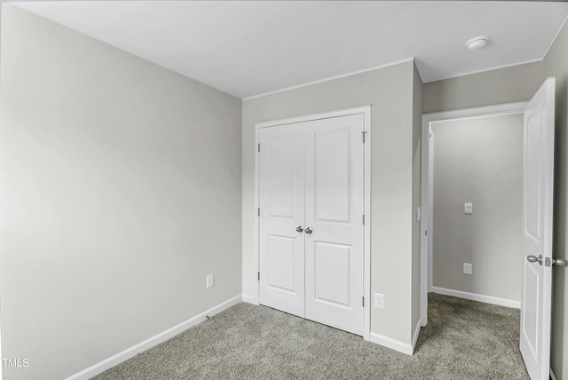 unfurnished bedroom featuring carpet, baseboards, and a closet