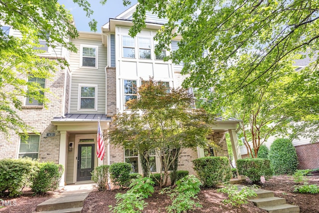 townhome / multi-family property with a standing seam roof and brick siding