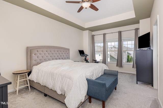 bedroom with light colored carpet, baseboards, and a tray ceiling
