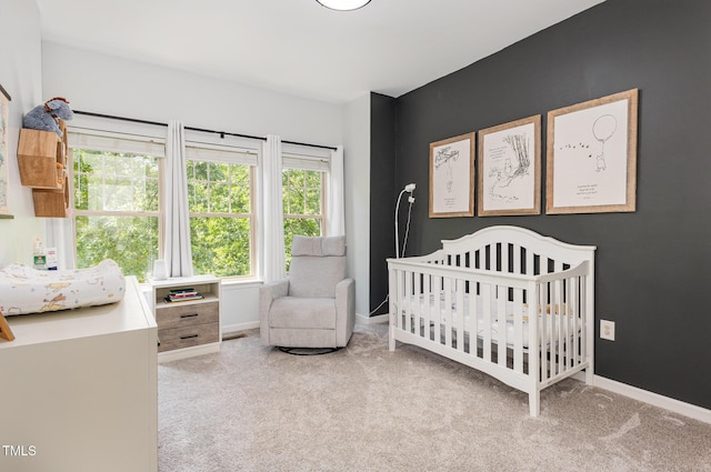 carpeted bedroom featuring baseboards and a nursery area