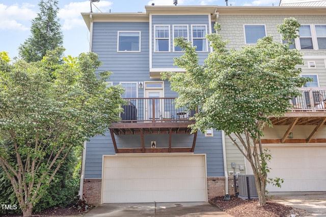 rear view of property with a garage, a balcony, driveway, central AC, and brick siding