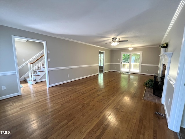 unfurnished living room with ceiling fan, dark wood finished floors, crown molding, a fireplace, and stairway