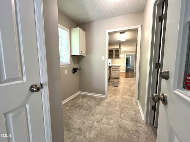laundry room with a textured ceiling and baseboards
