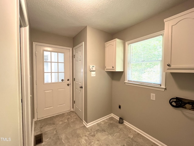clothes washing area featuring a textured ceiling, electric dryer hookup, baseboards, and cabinet space