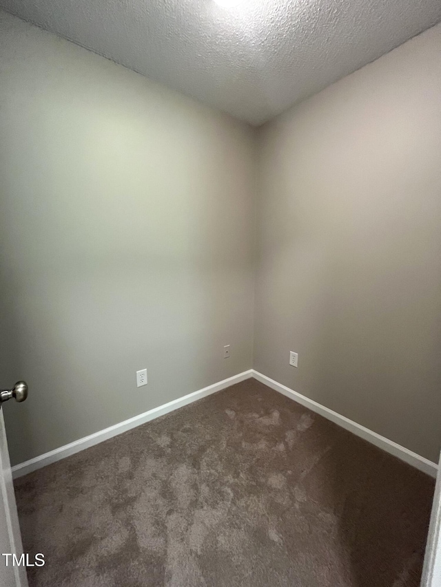 empty room featuring dark colored carpet, baseboards, and a textured ceiling