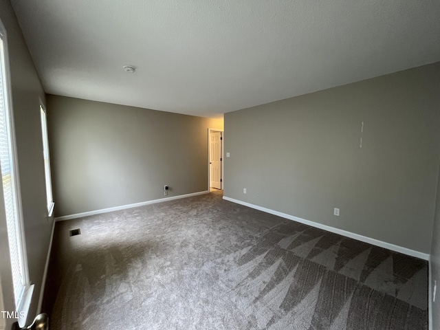 empty room with dark colored carpet and baseboards