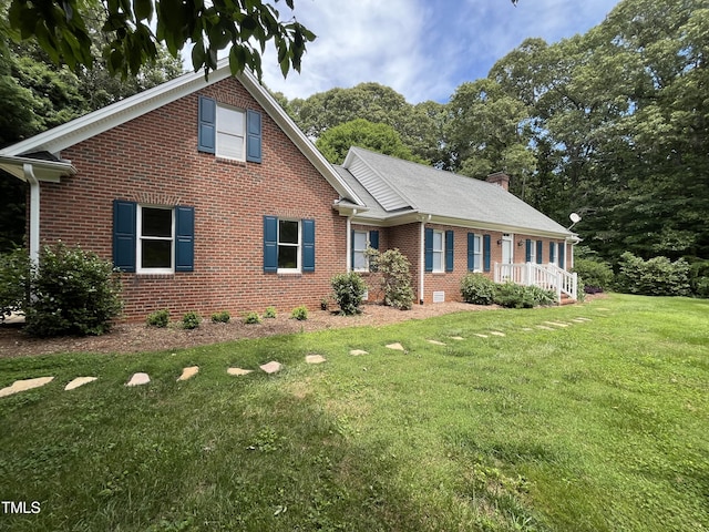 view of front facade with brick siding, a front yard, and a chimney