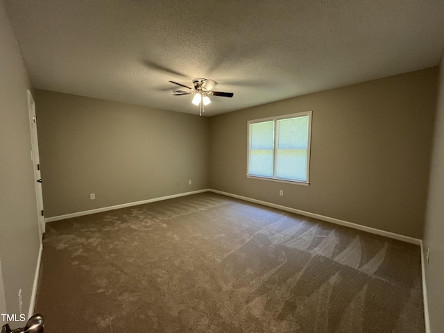 empty room featuring a ceiling fan, dark carpet, baseboards, and a textured ceiling