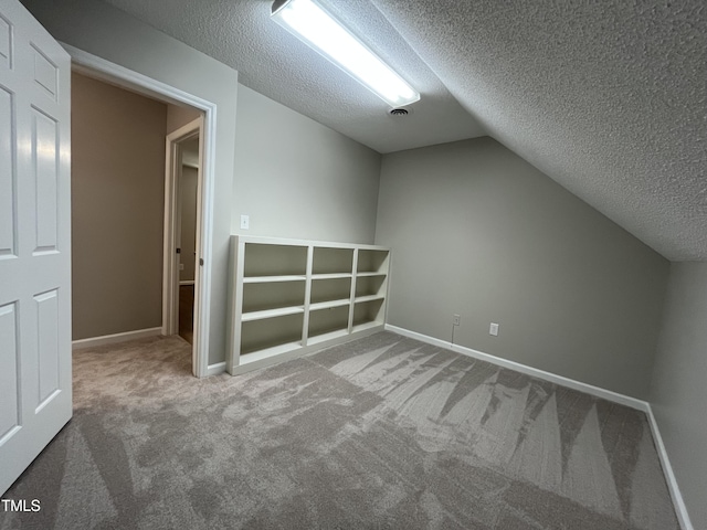 bonus room featuring a textured ceiling, carpet floors, lofted ceiling, and baseboards