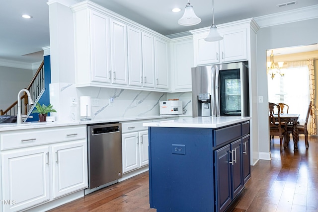 kitchen with appliances with stainless steel finishes, blue cabinetry, crown molding, a chandelier, and white cabinets