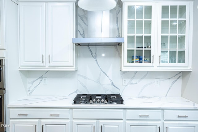 kitchen with exhaust hood, appliances with stainless steel finishes, glass insert cabinets, and white cabinets