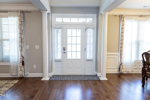 foyer entrance featuring decorative columns, healthy amount of natural light, ornamental molding, and a wainscoted wall