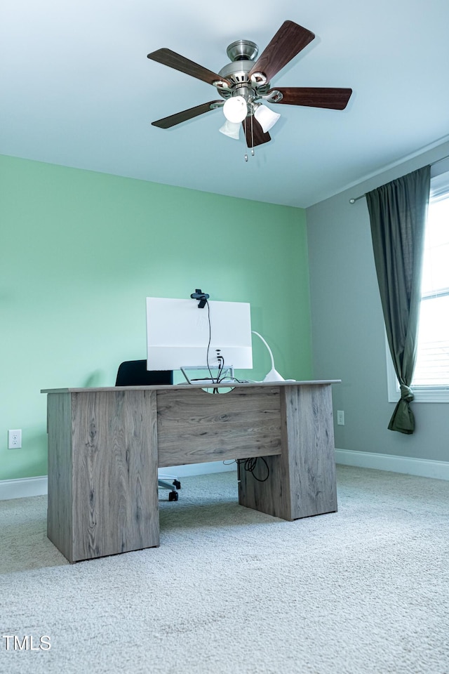 carpeted office space with ceiling fan and baseboards