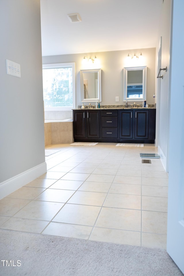 full bath with tile patterned floors, a garden tub, double vanity, and baseboards