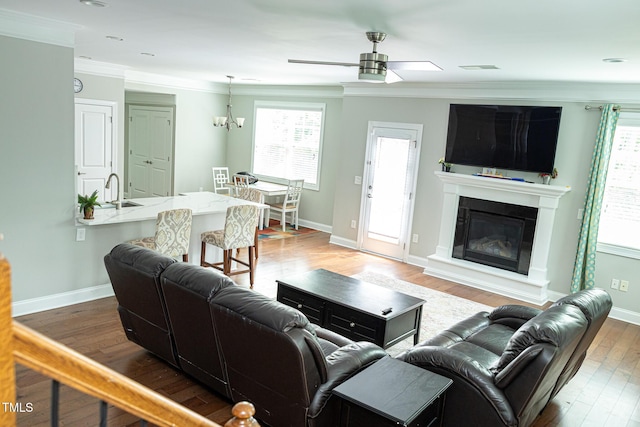 living room with crown molding, hardwood / wood-style floors, a ceiling fan, healthy amount of natural light, and baseboards