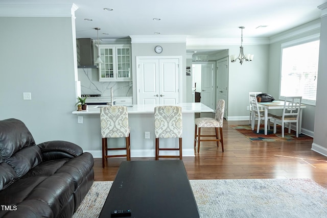 living area with ornamental molding, dark wood finished floors, baseboards, a chandelier, and recessed lighting