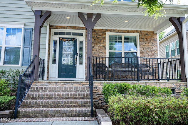 doorway to property with a porch and stone siding