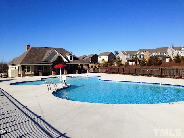 community pool featuring a residential view, fence, and a patio area