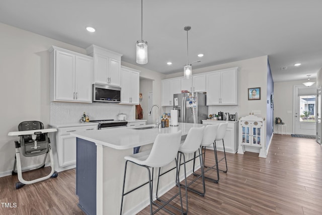 159 Wood Orchid Ln, Garner, NC 27529 - kitchen with stainless steel appliances, a sink, decorative backsplash, wood finished floors, and a center island with sink