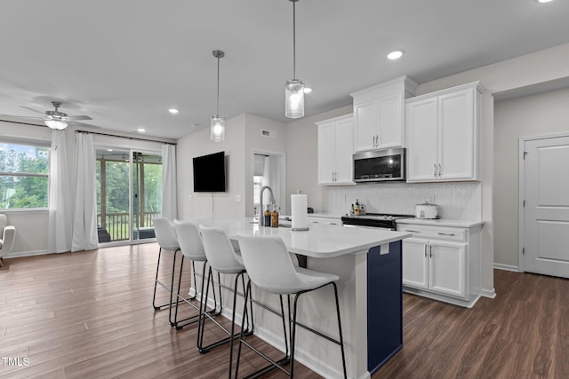 159 Wood Orchid Ln, Garner, NC 27529 - kitchen featuring stainless steel appliances, light countertops, an island with sink, a breakfast bar, and dark wood finished floors