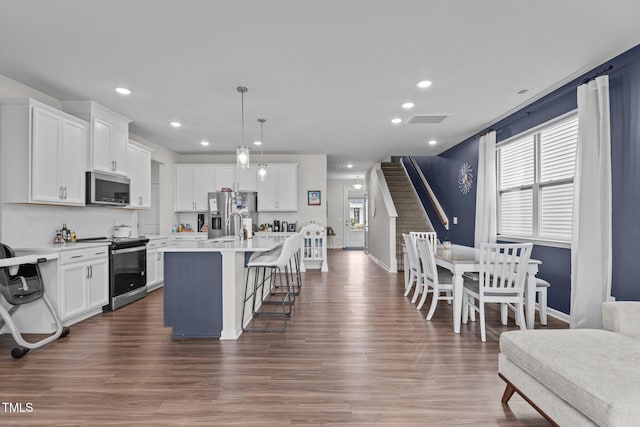 159 Wood Orchid Ln, Garner, NC 27529 - kitchen with appliances with stainless steel finishes, light countertops, a kitchen bar, white cabinets, and recessed lighting