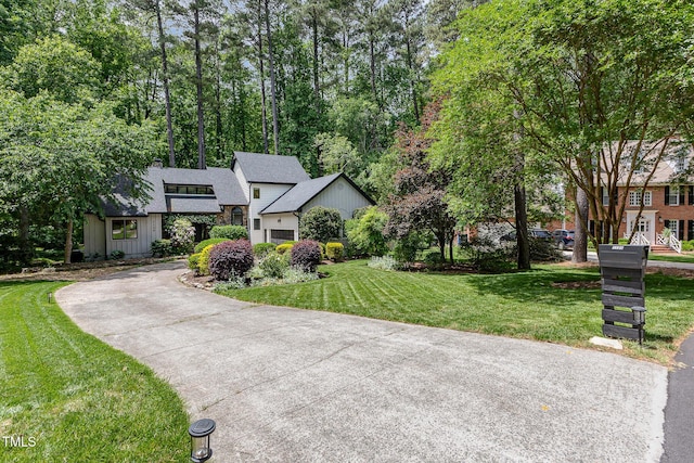 view of front facade featuring a front lawn, board and batten siding, driveway, and a shingled roof