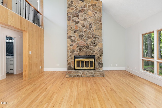 unfurnished living room with high vaulted ceiling, wood finished floors, a fireplace, and baseboards