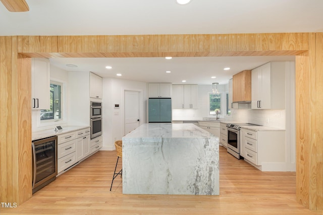 kitchen featuring beverage cooler, appliances with stainless steel finishes, light wood-style flooring, a breakfast bar area, and recessed lighting