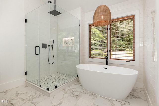 bathroom featuring marble finish floors, a stall shower, healthy amount of natural light, and a soaking tub