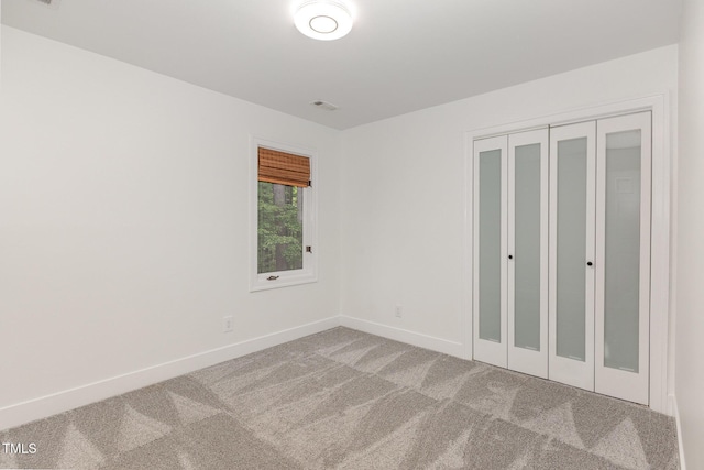 unfurnished bedroom featuring baseboards, carpet, and a closet