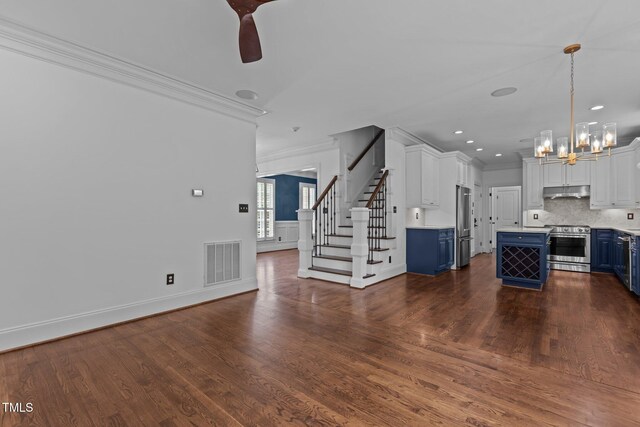 3323 Cheswick Dr, Raleigh, NC 27609 - unfurnished living room with crown molding, stairway, a chandelier, dark wood finished floors, and ceiling fan