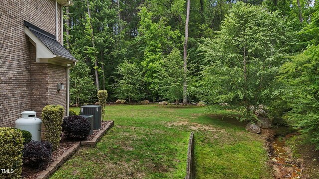 3323 Cheswick Dr, Raleigh, NC 27609 - view of grassy yard featuring central AC and a view of trees