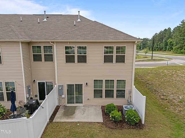 back of property with a patio area, a shingled roof, and central AC unit