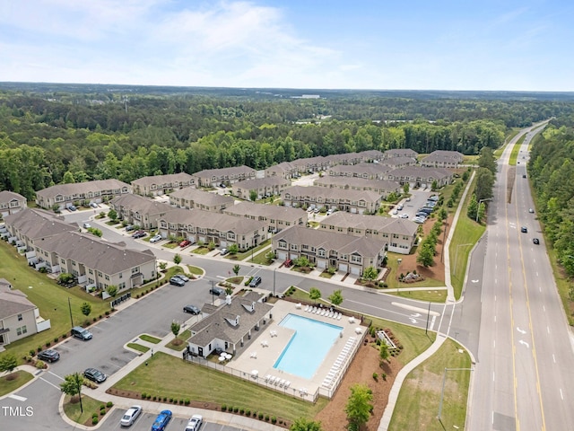aerial view of property's location featuring a pool area, a heavily wooded area, and nearby suburban area