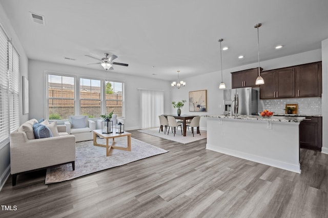 living room with wood finished floors, ceiling fan, recessed lighting, a chandelier, and baseboards