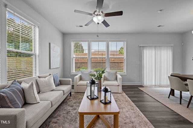 living area featuring a ceiling fan, dark wood finished floors, and baseboards