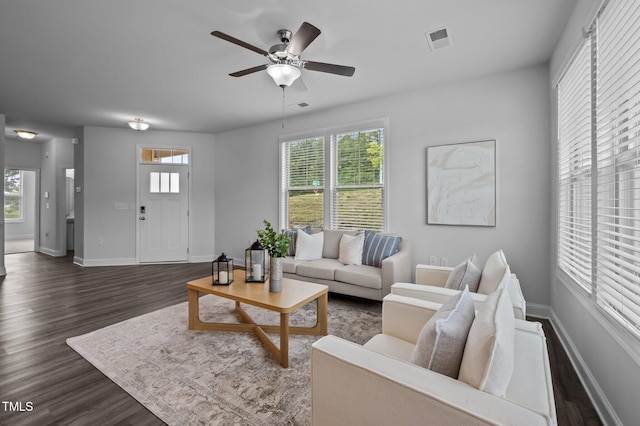 living room with dark wood-style flooring, a ceiling fan, and baseboards