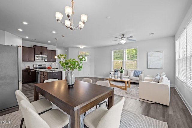 dining area with dark wood-style flooring, a ceiling fan, recessed lighting, baseboards, and a chandelier