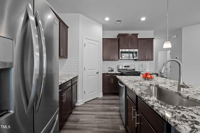 kitchen featuring appliances with stainless steel finishes, a sink, dark wood-type flooring, decorative backsplash, and recessed lighting