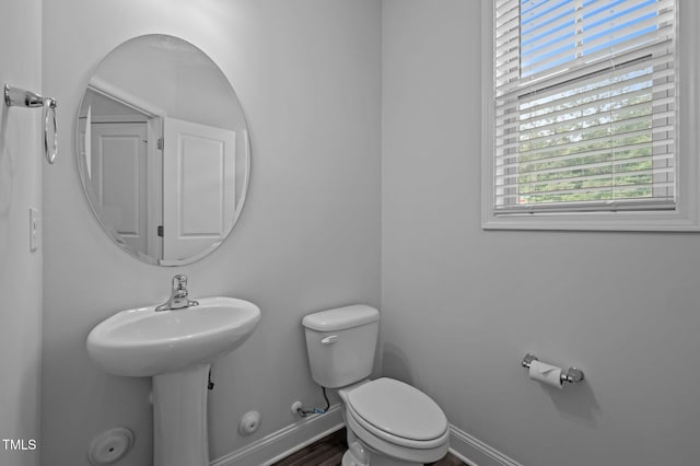 half bathroom featuring toilet, baseboards, and wood finished floors