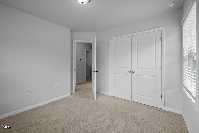 unfurnished bedroom with light carpet, baseboards, and a closet