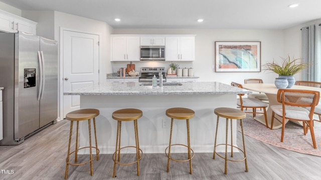 209 Wood St, La Grange, NC 28551 - kitchen featuring stainless steel appliances, light wood-type flooring, white cabinets, a center island with sink, and recessed lighting