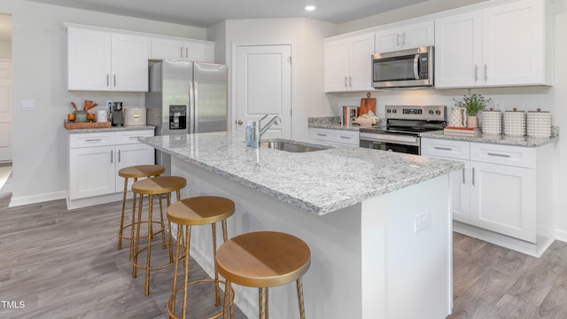 209 Wood St, La Grange, NC 28551 - kitchen featuring stainless steel appliances, a sink, light wood-type flooring, white cabinets, and a kitchen bar